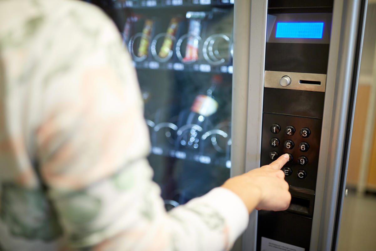 Studentin wählt etwas am Getränkeautomat aus